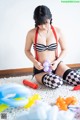 A woman in a black and white striped bikini sitting on the floor.