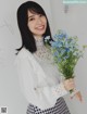 A woman holding a bunch of blue flowers in her hand.