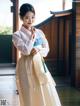 A woman in a white and blue hanbok is posing for a picture.