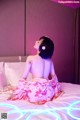 A woman in a pink kimono sitting on a bed.