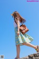 A woman walking on a stone wall with a brown bag.