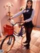 A woman in a school uniform standing next to a bicycle.