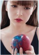 A woman holding a red and blue apple in her hands.