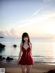 A woman in a red dress standing on a beach.