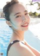 A woman in a black and white polka dot bathing suit by a pool.