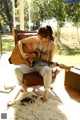 A woman sitting on a chair playing a guitar.