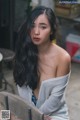 A woman with long black hair sitting on a chair.