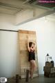 A woman leaning against a wooden wall in a room.