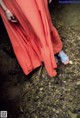 A woman in a red dress standing on a rocky ground.