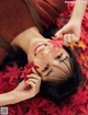 A woman laying on the ground surrounded by red leaves.