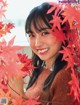 A woman with long black hair and a brown sweater smiles at the camera.