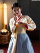 A woman in a kimono standing in front of a lamp.