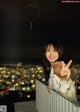 A young woman standing on top of a building at night.